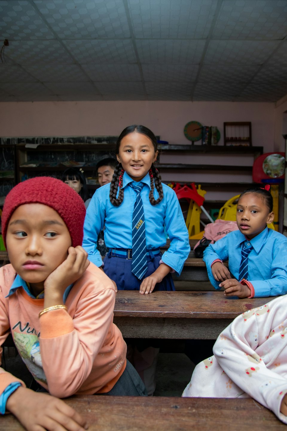 Siswa berseragam biru berinteraksi di ruang kelas.